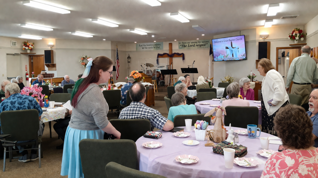 Church fellowship gathering at Grace Baptist Church with members seated at tables enjoying food and conversation in a welcoming community setting
